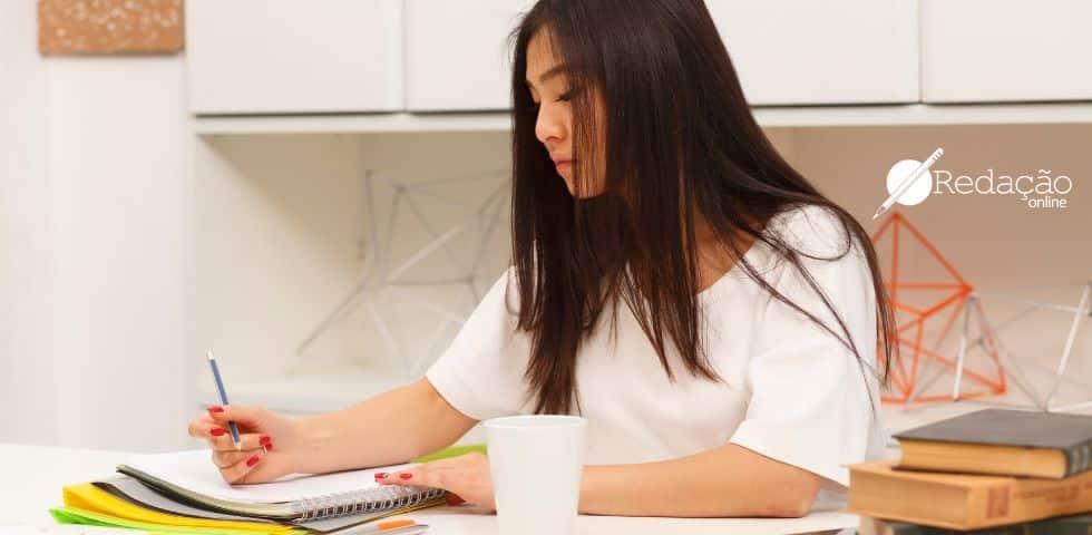 menina escrevendo no caderno com caneta